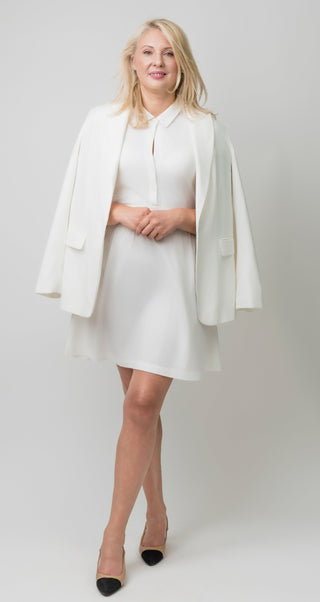 Woman wearing a white dress with a matching jacket on a plain background