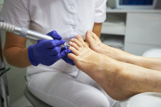 Person receiving a foot treatment with a handheld device in a clinical setting.