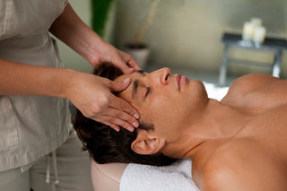 A man receiving a facial massage from a female therapist, with a focus on the facial treatment.