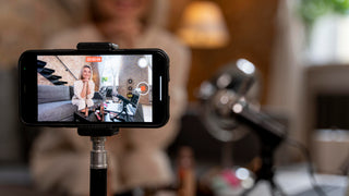 Smartphone on a stand displaying a video call with a blurred indoor background