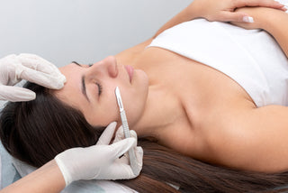 A person receiving a Dermaplaning facial treatment, where dead skin cells and fine hair are being removed from the face with a tool, in a beauty salon setting.