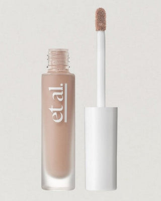 Cosmetic concealer bottle with applicator on a light gray background