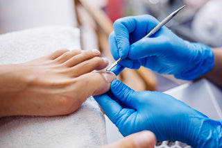 A close-up of a man's foot during a spa pedicure treatment, showing a professional performing a precise cuticle trim.