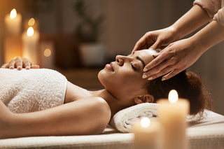 Woman receiving a head massage in a spa setting with candles and soft lighting.