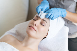 A person receiving a facial cleansing treatment from a professional, with focus on the skin cleansing process.