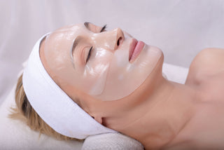 A person lying down with a hydrogel face mask applied to their face, presumably experiencing a skin firming and lifting treatment.